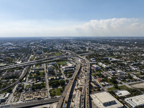 Aerial view of a sprawling cityscape with a complex network of highways, buildings, and the distinct form of the Kaseya Center, Miami, Florida, USA.