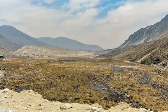 Barren high-altitude valley with rocky terrain and distant mountains, dramatic Himalayan landscape in North Sikkim, India.
