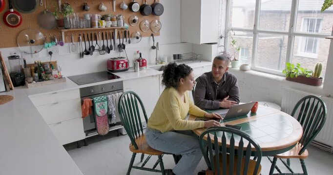 College students laughing together while using laptop in a kitchen