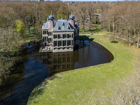 Aerial view of a majestic castle rises from the tranquil waters, its grey stone contrasting with the surrounding vibrant green landscape, Oegstgeest, Zuid-Holland, Netherlands.