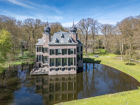 Aerial view of the castle reflected on the water, surrounded by trees and green fields, Landgoed Oud Poelgeest, Oegstgeest, Zuid-Holland, Netherlands.