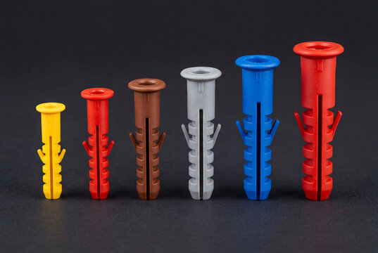 Colorful Plastic Wall Plugs in Various Sizes Arranged on Dark Background