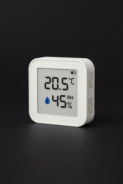 White Digital Thermometer and Hygrometer Displaying Temperature and Humidity on Black