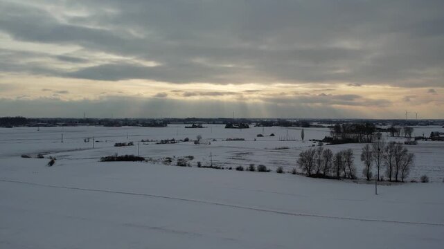 Dramatic winter landscape with sun rays breaking through clouds, aerial view.