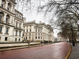 Naklejka premium London street scene with historic buildings, wet pavement, and people under umbrellas