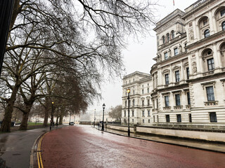Naklejka premium London street view with grand historic buildings and bare trees along a damp red pavement