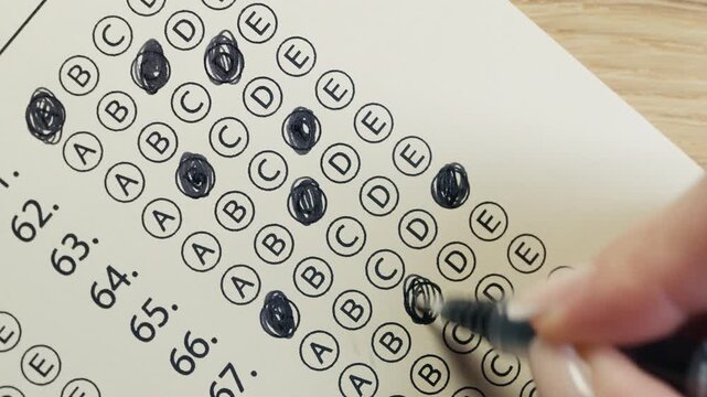 Close-up footage of a student completing a test and marking answers on paper. Concept of exams, education, knowledge testing, certification and academic achievement.