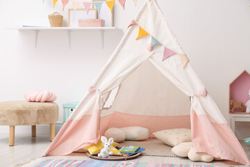 Cute wigwam with pillows, books and toys in stylish child's room © New Africa