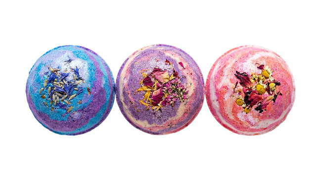 Three colorful bath bombs with dried flowers and herbs, isolated on transparent background