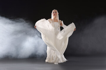 Fototapeta premium Beautiful girl dressed as elf on black background with smoke