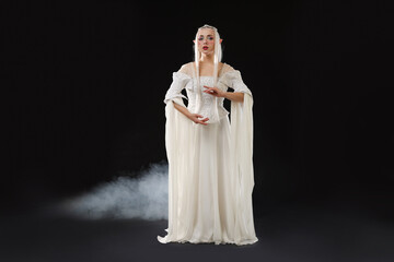 Fototapeta premium Beautiful girl dressed as elf on black background with smoke