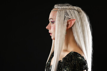 Fototapeta premium Beautiful girl dressed as elf on black background, space for text