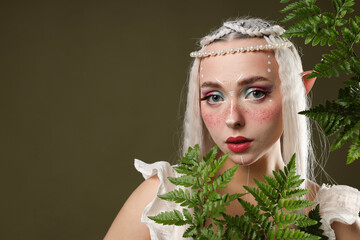 Fototapeta premium Beautiful elf girl with floral decor on dark olive background, space for text