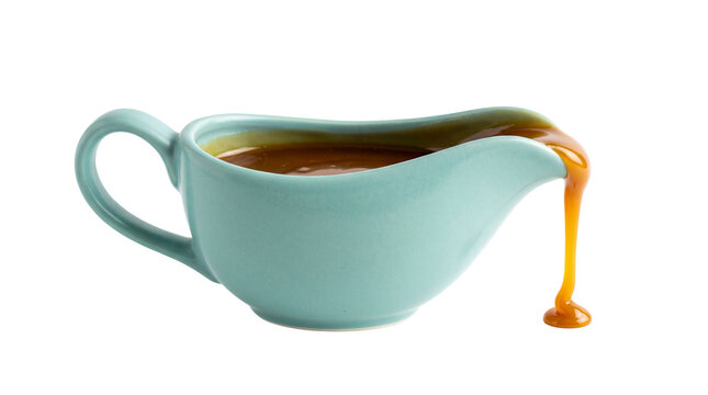 Light blue ceramic gravy boat with thick caramel sauce pouring out, isolated on transparent background