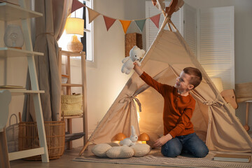 Little boy playing with toys near wigwam at home © New Africa