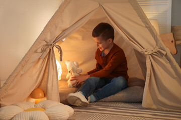 Little boy playing with toys in wigwam at home © New Africa