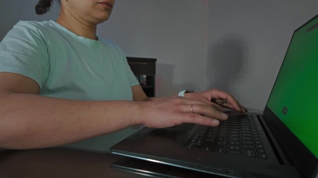 Focused Woman Types on Laptop with Green Screen, Ideal for Digital Content and Remote Work