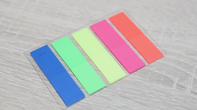Colorful sticky page markers arranged on light wooden surface. Clean stationery composition for office and study organization concept.