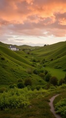 Obraz premium A serene countryside scene during sunset with green hills, a winding road, and houses in the valley.