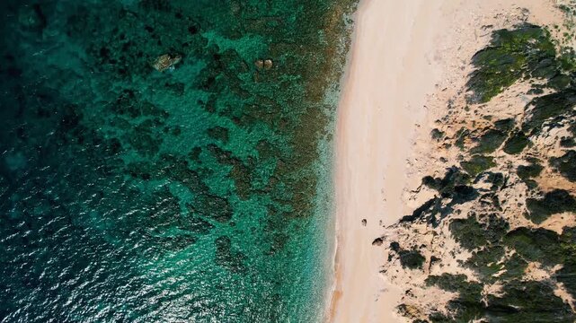4k video with top down view, overflying the southern coast of Lesvos island, Greece, with crystal green waters and rocks by a sandy shore