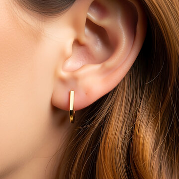 A woman wearing elegant gold hoop earrings in her earlobe