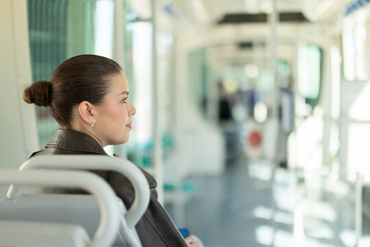 Portrait of woman in black leather jacket on a tram. Traveling by public transport