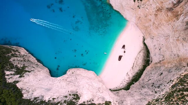 4k - Aerial view of Navagio (Shipwreck) beach in Zakynthos, Ionian Sea, Greece, a golden sand shore with turquoise waters and an old, rusty shipwreck slowly getting eaten by the sand. 