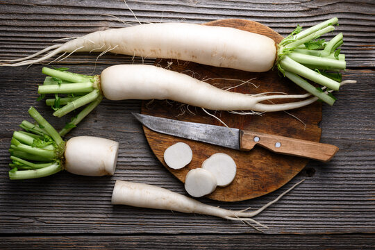 Daikon radish with slices on wooden table, white radish, fresh root vegetable