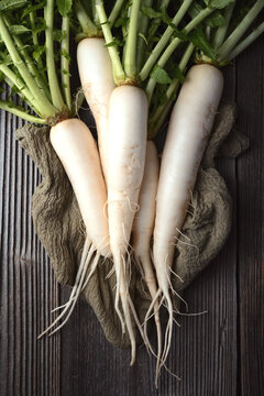 Daikon radish with long roots on textured wooden background, white radish, farm fresh vegetables