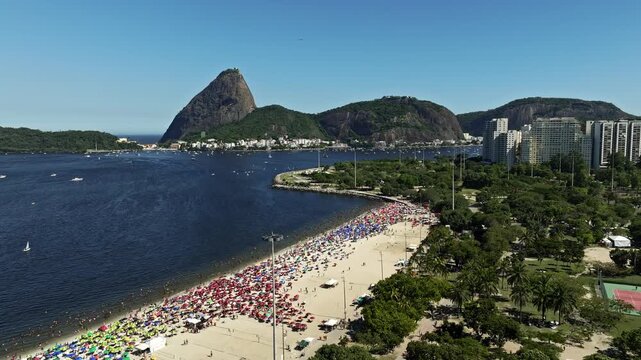 Aerial View, Drone Shot, Drone Footage of Aterro do Flamengo traveling out by trees of Flamengo landfill, the beach with sugar loaf mountain and boats in the sea in a summer day