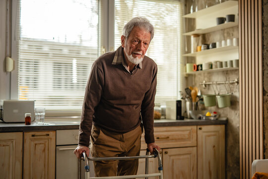 Senior man using walker for mobility in home kitchen