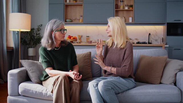 Mature woman tells story to old friend sitting in living room