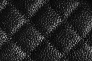 Fototapeta premium Close up, macro of black quilted leather texture with stitched diamond pattern, luxury material surface shining metal effect for fashion, upholstery or design wallpaper, rough, relief background