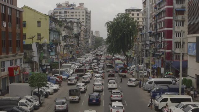 Cars and people moving through a congested urban street in an Asian city