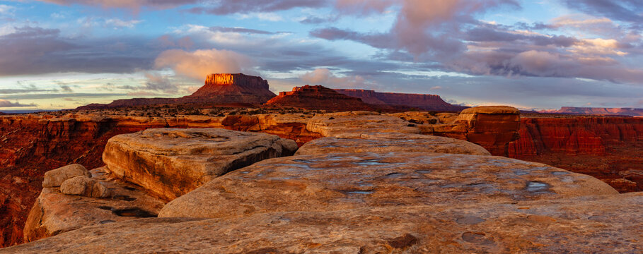 This scenic sunset panorama of Canyonlands National Park features White Crack with Junction Butte and the Island in the Sky rising above underneath a colorful sky.