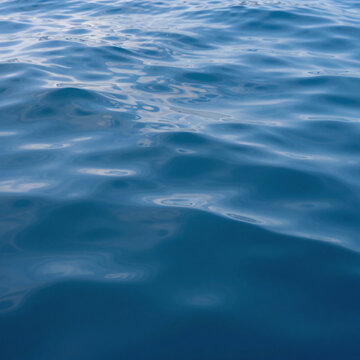 Kawaii Ocean Calm. Detailed Closeup Of Calm Ocean Blue Water With Sunshine And Clouds Above