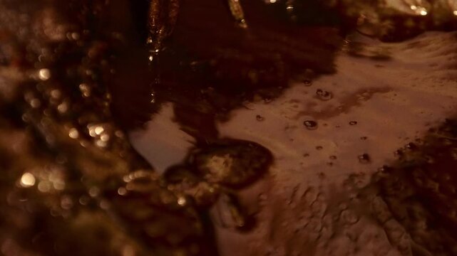 Crude oil bubbling and dripping from a pipe at an unregulated oilfield in Myanmar