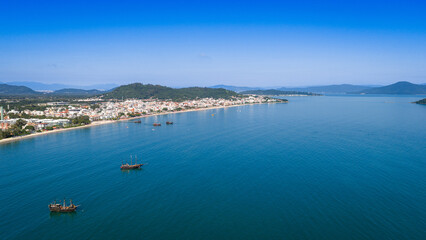 Obraz premium Aerial photograph of anchored boats on calm bay waters in front of Canavieiras beach town in Florianopolis.