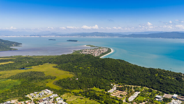 Wide aerial shot of Praia da Daniela sandy peninsula surrounded by calm sea in Florianopolis.