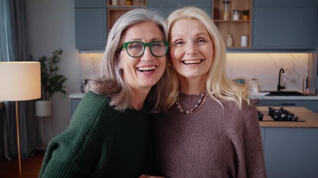 Senior women friends smile together for friendly home portrait