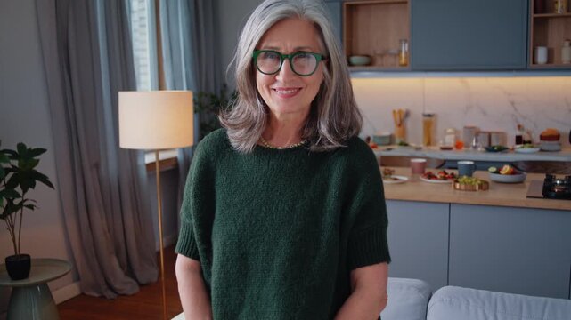 Aged woman stands in kitchen smiling in elegant home portrait