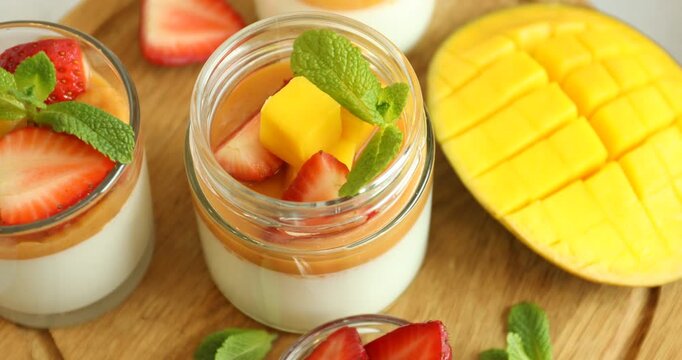 Delicious mango panna cotta, fruits and mint on table, above view
