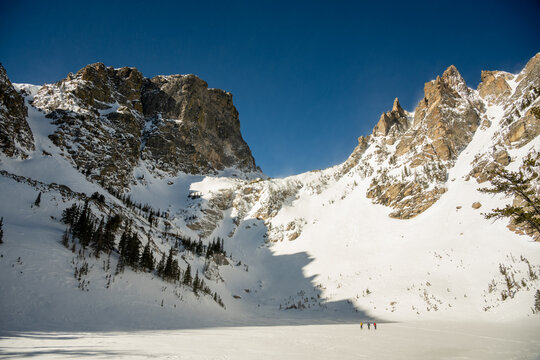 Three Skiiers Cross Frozen Emerald Lake In Winter