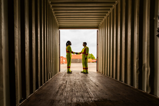 Successful handshake between diverse logistics specialists after a deal. Professional experts agreeing on maritime trade and freight transport operations inside a container shipyard depot.