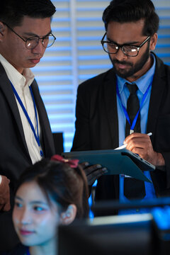 AI research team huddles late night innovators review complex machine learning model architecture discuss training data using tablet stylus futuristic lab code screens glow bright.