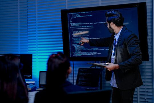 A focused male AI solutions architect in a futuristic control hub debates generative AI applications collaborating on a complex machine learning model with his team under atmospheric blue lighting.