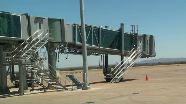 Airport Jet Bridge at Terminal Gate on Empty Tarmac under a clear blue sky.