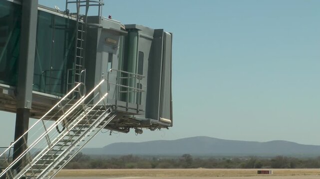 Airport Jet Bridge at Terminal Gate on Empty Tarmac under a clear blue sky.
