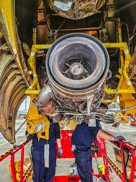 Two aviation technicians on a lift platform work together to install a jet engine APU in a hangar. Aircraft service and MRO concept..High quality photo