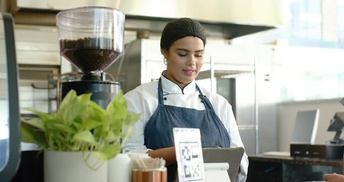 Customer extending card is starting payment, barista is tapping tablet at counter, finalizing order